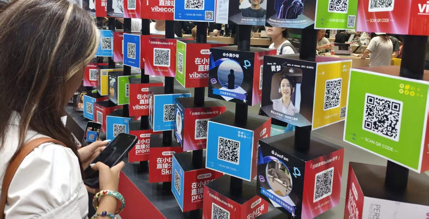Visitor scanning QR codes on a wall of rotating displays presenting AI agents and digital projects at WAIC Shanghai